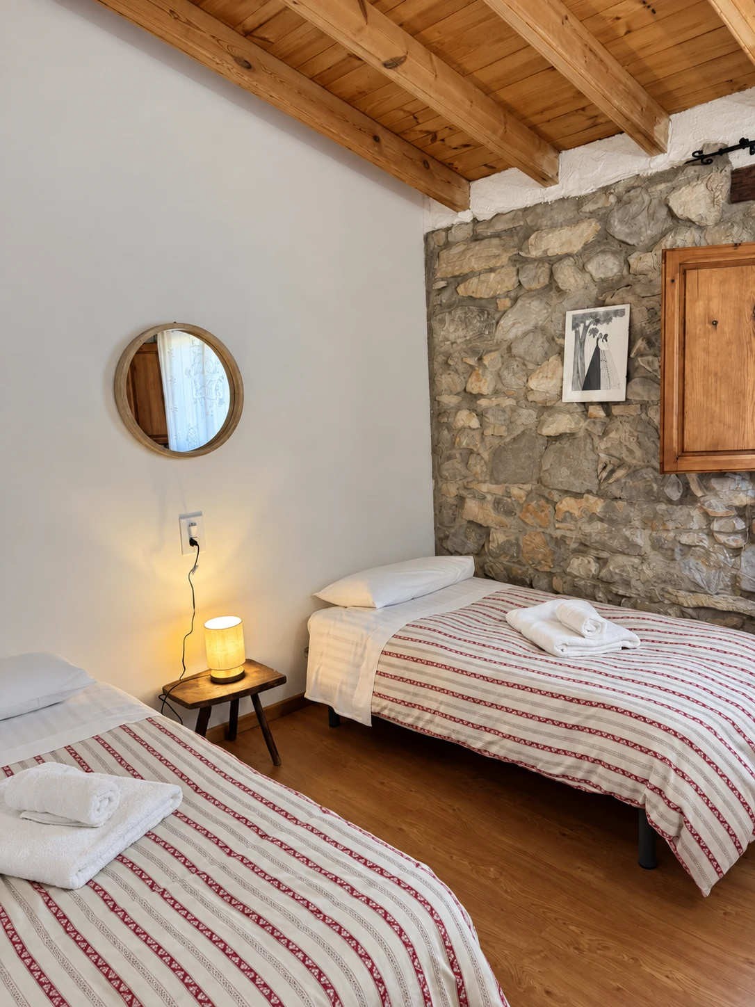 Dormitorio luminoso con vigas de madera y pared de piedra